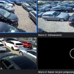 Podgląd z czterech kamer monitoringu wizyjnego, ukazujący parking samochodowy z różnymi pojazdami. Jeden z kanałów jest niedostępny i wyświetla ikonę ładowania.