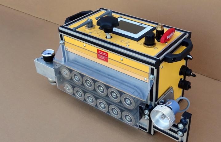 Żółto-czarne urządzenie z ekranem i elementami sterującymi, wyposażone w podwójny system rolek transportowych, potencjalnie do inspekcji lub czyszczenia rur.