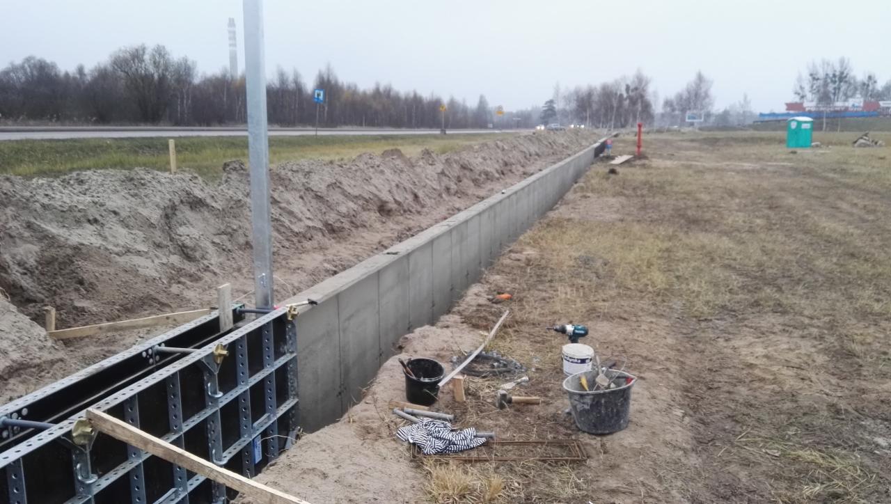 Budowa betonowego koryta odwadniającego przy drodze w Gdańsku, widoczne szalunki, narzędzia i przenośna toaleta w tle.