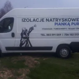 Biały samochód dostawczy z reklamą natryskowej izolacji pianką PUR, z ilustracją pracownika w kombinezonie ochronnym i numerami telefonów, zaparkowany na trawiastym terenie.