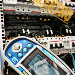 Panel rozdzielczy z zabezpieczeniami i przewodami, sprawdzany za pomocą miernika EurotestPV z wyświetlaczem pokazującym wyniki pomiarów.