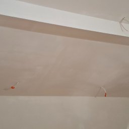 TermoGips Tomasz Buda - Gładka, biała powierzchnia sufitu po szpachlowaniu, z widocznymi przewodami elektrycznymi. Świeżo wykończone wnętrze, gotowe do dalszych prac.