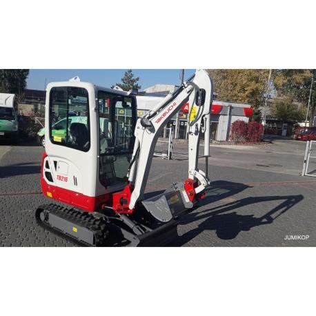 Kompaktowa, biało-czerwona mini koparka Takeuchi TB216 z łyżką, zaparkowana na parkingu z kostki brukowej, widoczny cień rzucany przez maszynę.