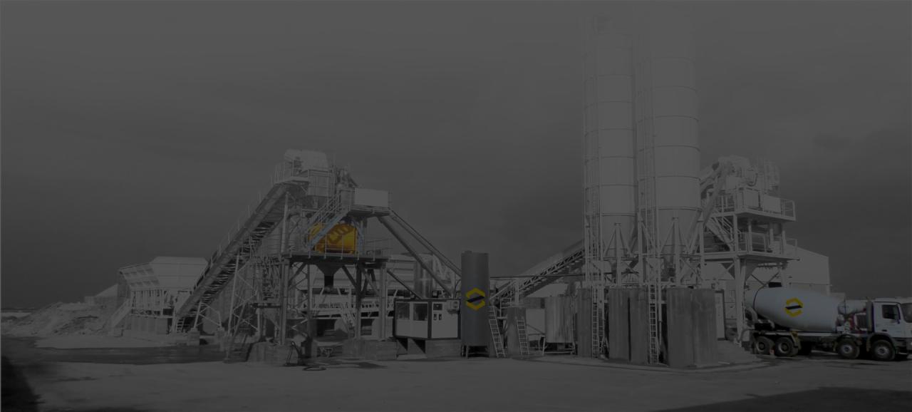 Kompleksowa instalacja mieszalni betonu w Staszowie z widocznym silosami, podajnikiem surowców i betonomieszarką na podwoziu ciężarowym w tle.