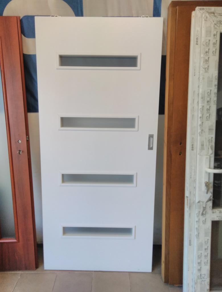 Białe, nowoczesne drzwi wewnętrzne z czterema poziomymi przeszkleniami, widoczne obok ramy innych drzwi i okna.