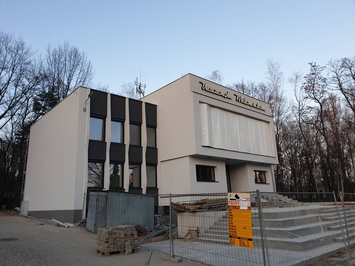 Budynek Urzędu Miasta w Tychach po remoncie elewacji, widoczne nowe tynki i odświeżona kolorystyka, teren budowy zabezpieczony barierkami.
