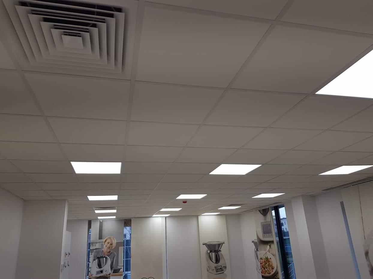 Pomieszczenie biurowe z nowo pomalowanym sufitem kasetonowym, widoczne kratki wentylacyjne i równomierne oświetlenie LED.