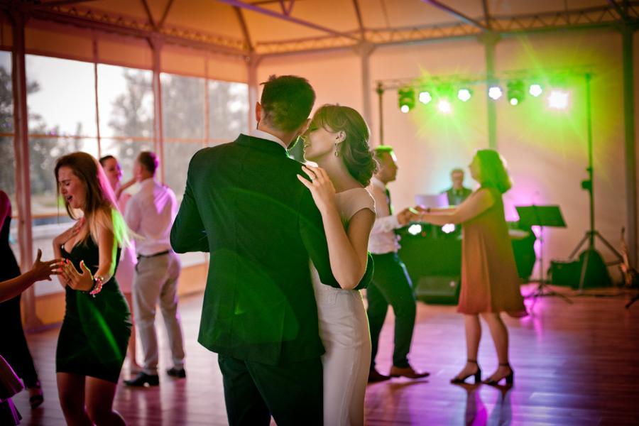 Para młoda tańczy podczas wesela, oświetlenie sceniczne w tle, parkiet odbija światła.