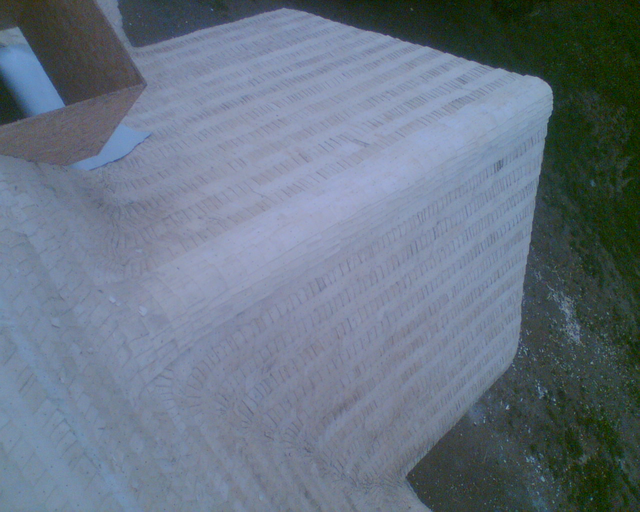 Surowy blat kamienny z widocznymi śladami obróbki, szlifowania i charakterystyczną teksturą, z elementami kartonu i papieru na powierzchni.