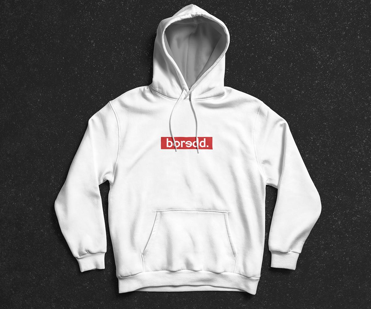 Biała bluza z kapturem z czerwonym prostokątnym logo 'boredd.' na tle ciemnej, teksturowanej powierzchni.
