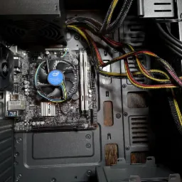 Wnętrze obudowy komputera stacjonarnego z zamontowaną płytą główną ASRock, procesorem Intel z chłodzeniem i widocznymi przewodami zasilającymi w czarnych oplotach z żółto-czerwonymi akcentami.