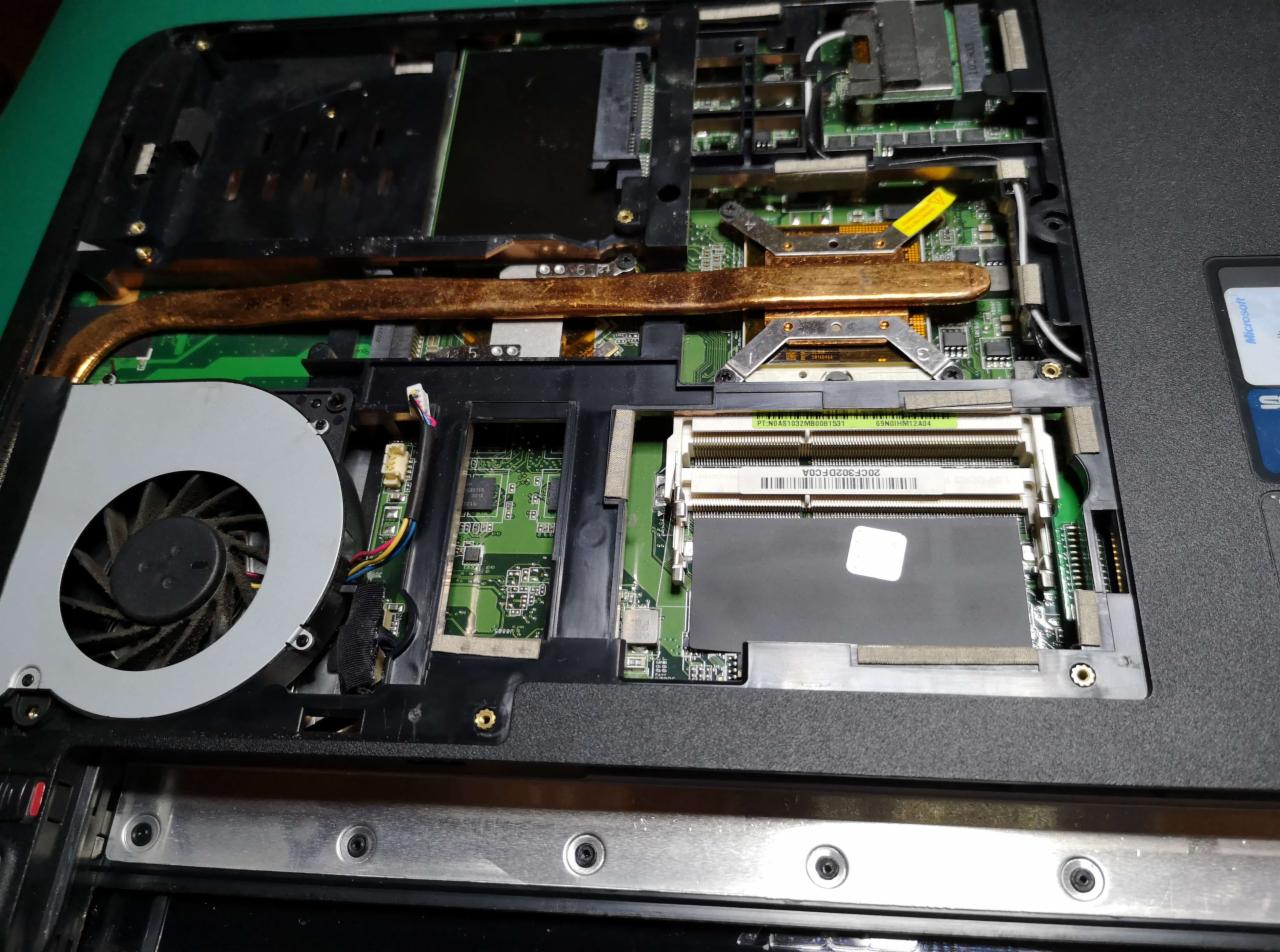 Wnętrze otwartego laptopa z widocznym układem chłodzenia, wentylatorem i modułem pamięci RAM. Widoczny kurz na wentylatorze.