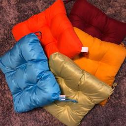 Mikolajczyk - Kaskada kolorowych poduszek na krzesła ogrodowe: turkusowa, limonkowo-zielona, pomarańczowa i bordowa, ułożone na dywanie z długim włosiem.