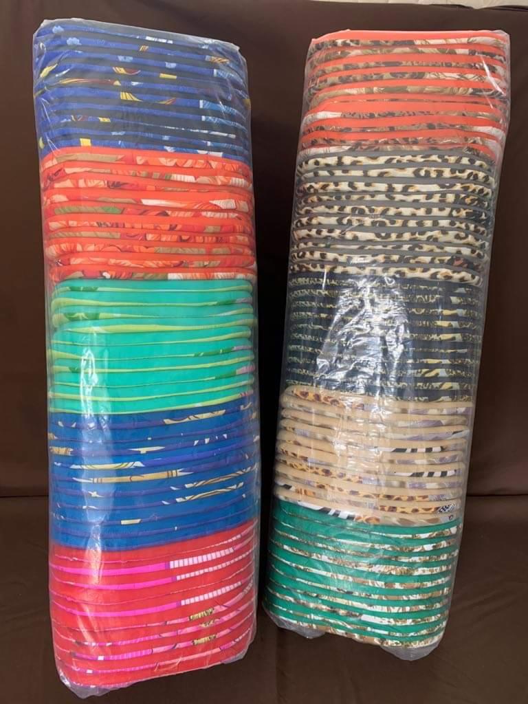 Dwa stosy kolorowych, okrągłych podkładek pod talerze w przezroczystej folii, jeden z dominującymi odcieniami niebieskiego, zieleni i czerwieni, drugi z motywami zwierzęcymi i pomarańczowymi...