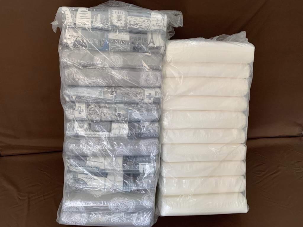 Dwa stosy zapakowanych wałków do powierzchni: jeden z wzorem paryskim w szarościach, drugi biały, leżące na brązowej powierzchni.