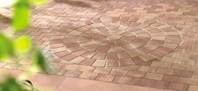 Ułożona kostka brukowa w odcieniach brązu i beżu tworząca wzór okręgu na patio, z roślinnością w lewym dolnym rogu.