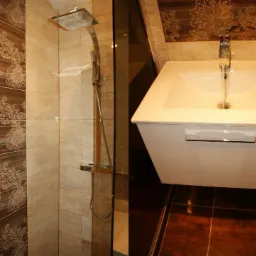 Wykończona łazienka z kabiną prysznicową typu walk-in, umywalką nablatową z szafką i dekoracyjnymi płytkami w odcieniach beżu i brązu z motywem kwiatowym.