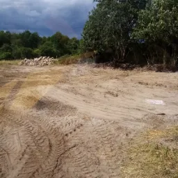 Teren w Starym Worowie przygotowany pod budowę, widoczne ślady opon ciężkiego sprzętu i pryzma kamieni w tle.