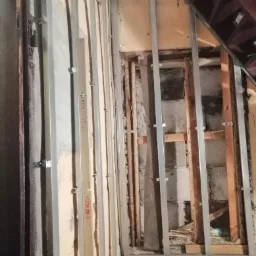 Montaż metalowego stelażu pod okładzinę w Sekursku, widoczne profile pionowe i poziome, fragment schodów w tle.