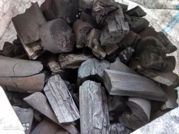 Kawałki węgla drzewnego o różnej wielkości i kształtach, ułożone w worku z widocznymi niebieskimi paskami.