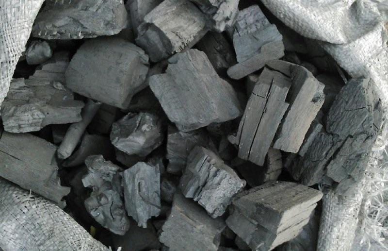 Kawałki węgla drzewnego o nieregularnych kształtach w jutowym worku, widoczne drobne pęknięcia i słoje drewna.