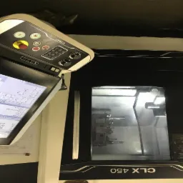 Nowoczesna frezarka CNC CLX 450 z panelem sterowania, widok na wnętrze komory roboczej z zamocowanym detalem.