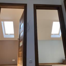 Darex - Dwa drewniane ościeżnice z widokiem na poddasze z oknami dachowymi, ściany pomalowane na różne kolory, widoczne gniazdka elektryczne i wystające kable.