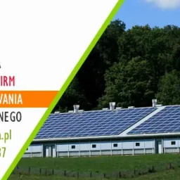 Instalacja paneli słonecznych na dachu budynku gospodarczego, reklama firmy OZE Ekologia z informacją o 100% dofinansowania i braku wkładu własnego.