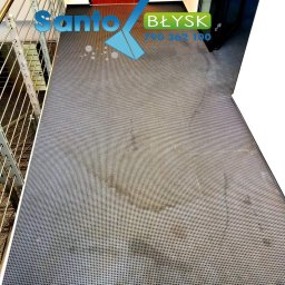 Santo Błysk - Szary dywan z drobnymi oczkami na schodach, widoczne plamy i logo firmy Santo Błysk w górnej części kadru.