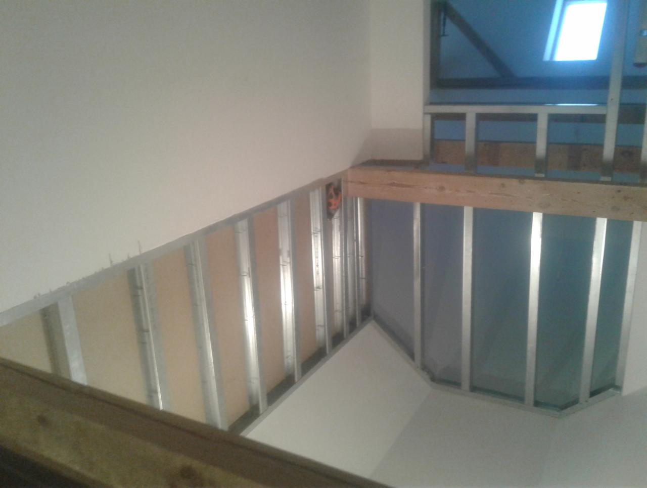 Konstrukcja metalowa pod płyty gipsowo-kartonowe na poddaszu, widoczne profile i fragment płyty, okno dachowe w tle.