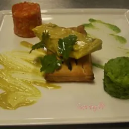 Elegancko podane danie na białym kwadratowym talerzu: ryba w sosie na ciastku francuskim, z dodatkiem pomarańczowego i zielonego puree oraz artystycznie rozprowadzonego sosu.