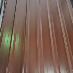 Brązowe arkusze blachy trapezowej, ułożone jeden na drugim, widoczne z bliska pod lekkim kątem.