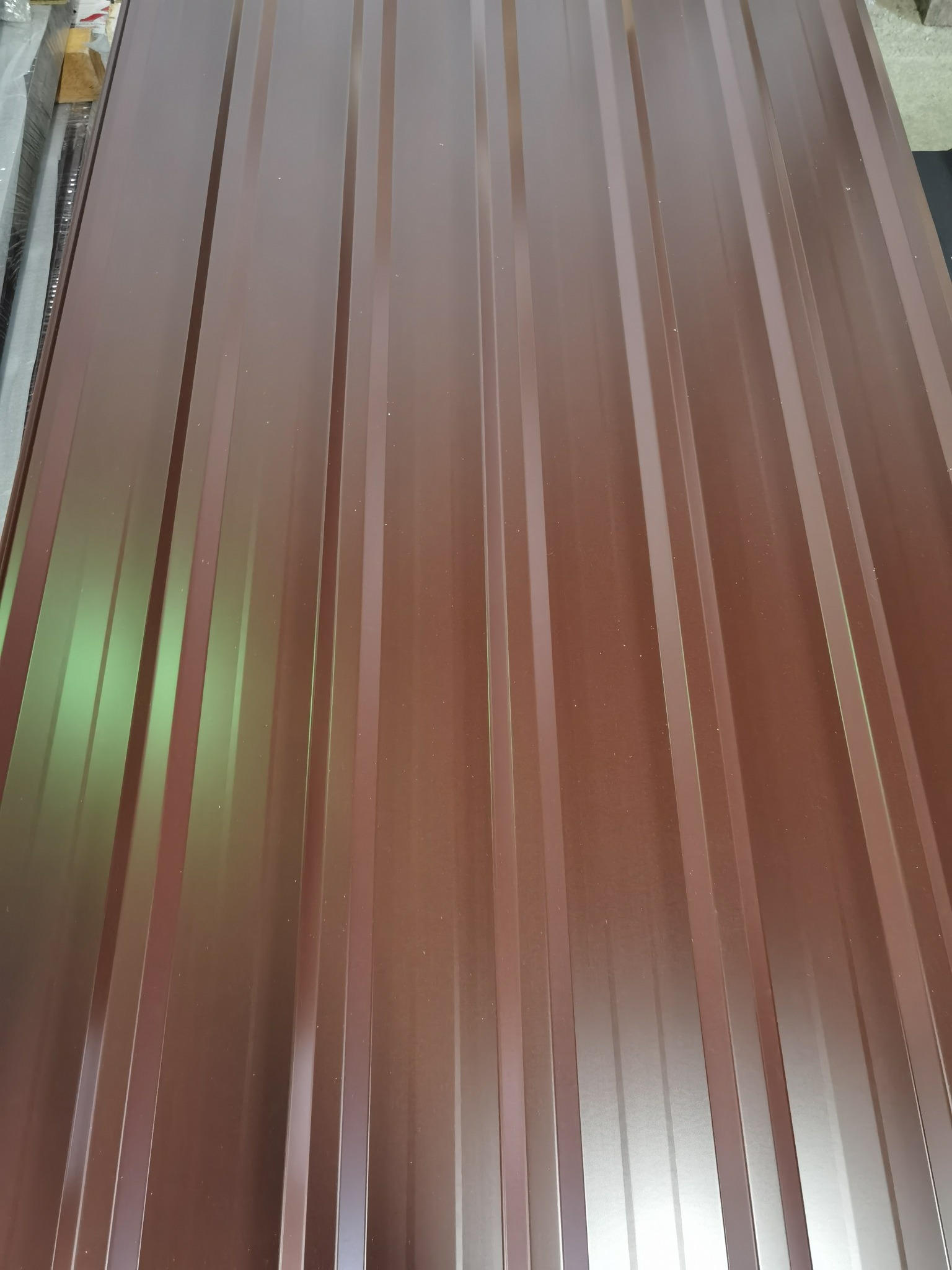 Brązowe arkusze blachy trapezowej, ułożone jeden na drugim, widoczne z bliska pod lekkim kątem.