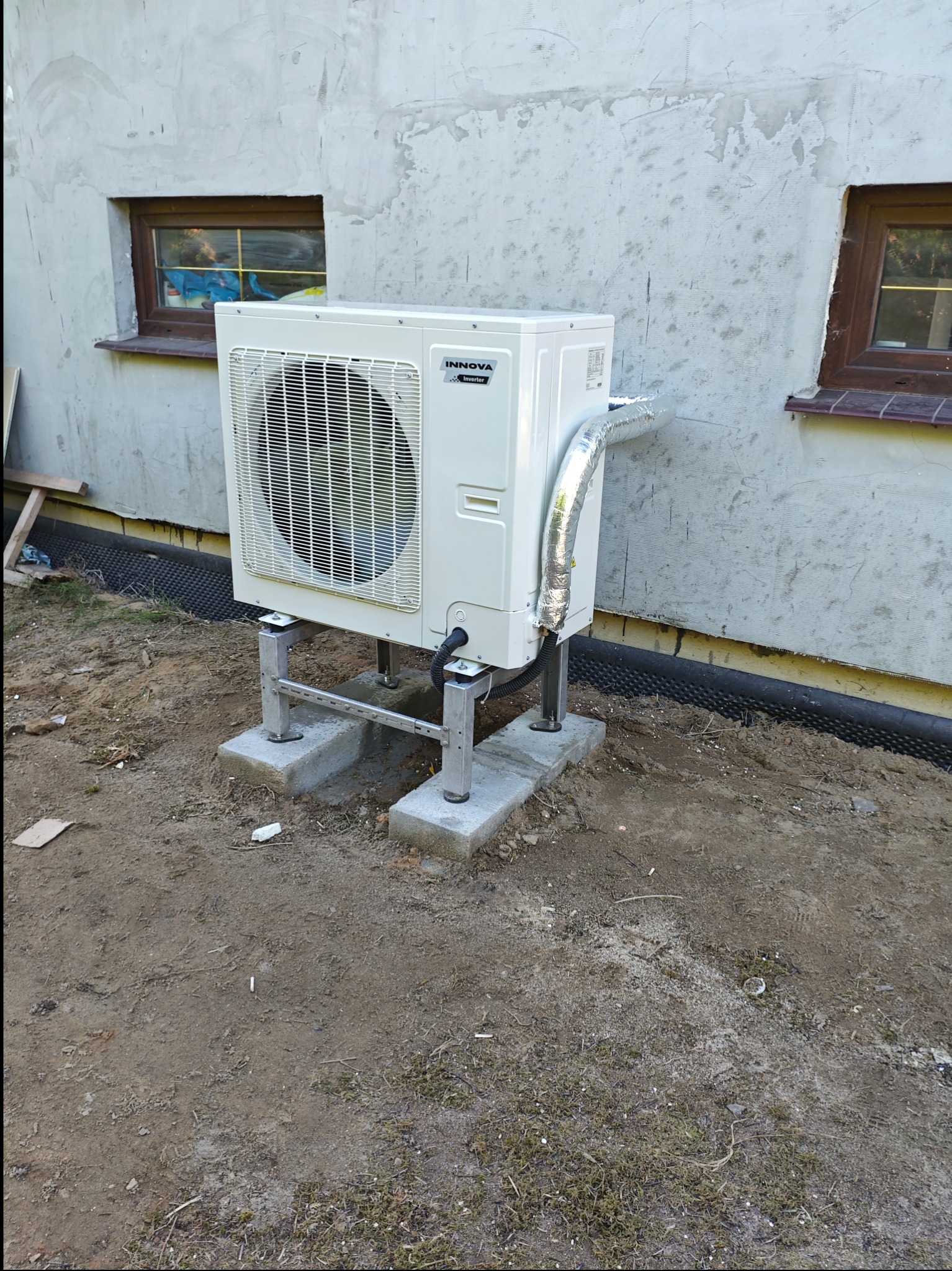 Pompa ciepła Innova jednostka zewnętrzna na nierdzewnym stelażu na wymurowany fundamencie z bloczków betonowych.