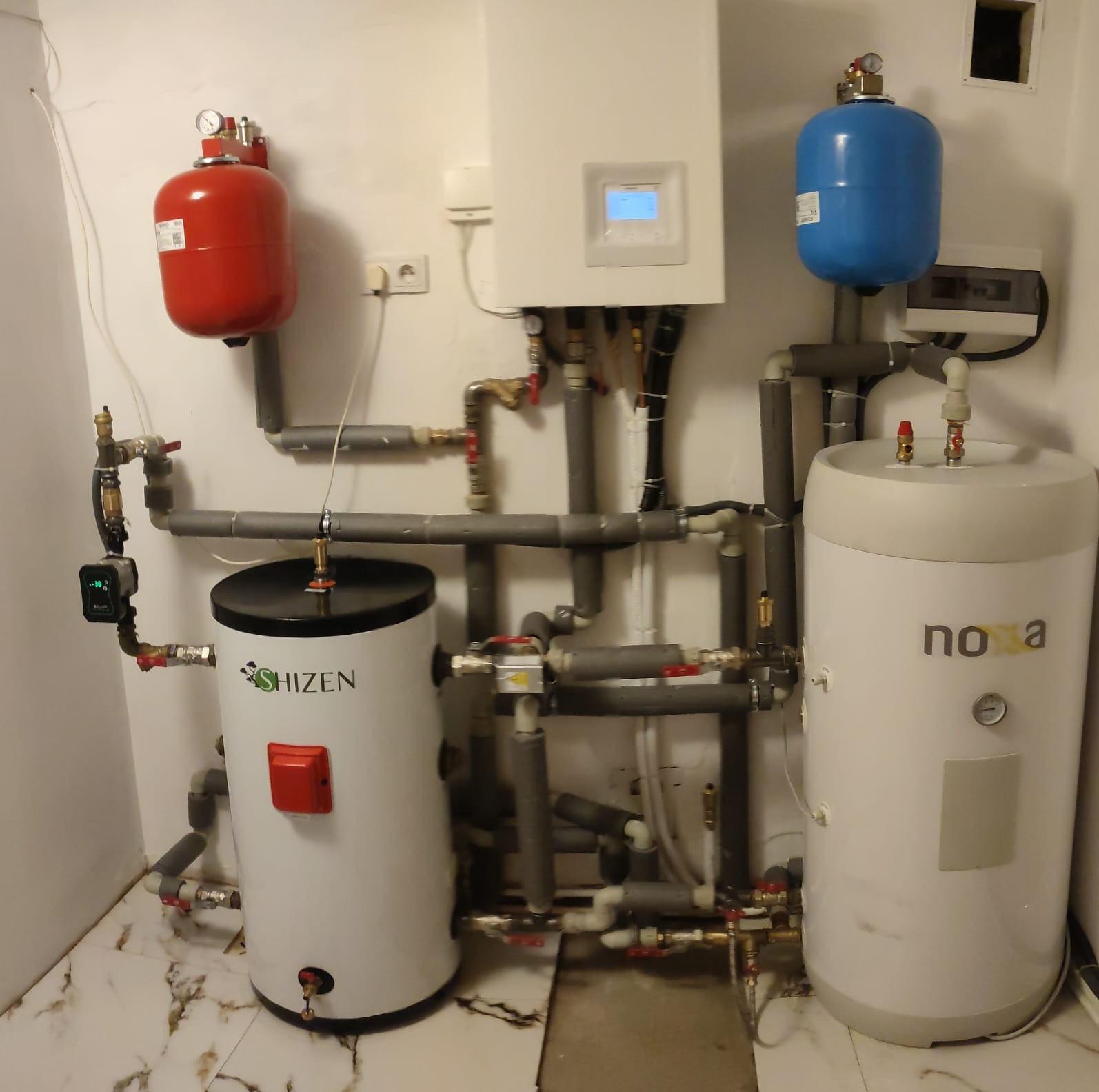 Instalacja pompy ciepła w Jaczkowicach: widok na jednostkę wewnętrzną Hitachi Yutaki S, zbiornik wody użytkowej Nova i bufor Shizen, z licznymi rurami i zaworami.