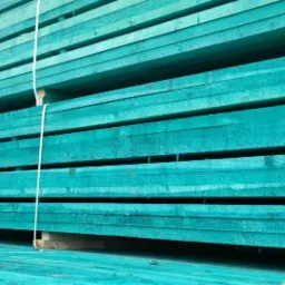 Stos tarcicy budowlanej w kolorze turkusowym, związany białym sznurkiem, ułożony na palecie.