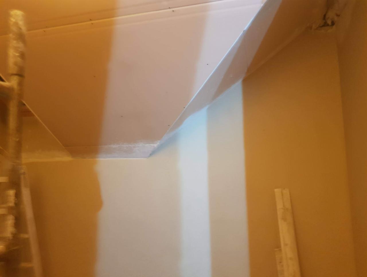 Ściana po nałożeniu tynku maszynowego, widoczne niedoskonałości w narożniku i ślady po drabinie.