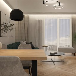 JTG Design - Jasne wnętrze mieszkania z parkietem w jodełkę. Stół z krzesłami, sofa w odcieniach zieleni, telewizor, okno z zasłonami i designerskie lampy.