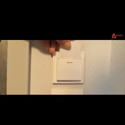 Wkładanie białej karty do białego czytnika kart zamontowanego na ścianie, widoczny fragment dłoni.