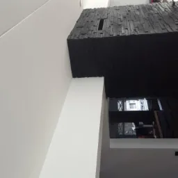 Nowoczesne wykończenie wnętrza z czarną ścianą z imitacji kamienia i minimalistyczną, białą ścianą, widok z dołu.