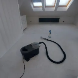 Profesjonalny odkurzacz piorący na tle jasnego, świeżo wypranego dywanu w przestronnym pokoju na poddaszu z oknami dachowymi