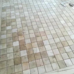 Fragment drewnianego tarasu ułożonego z kwadratowych elementów, widoczne słoje drewna i rama konstrukcji.