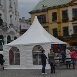 Go Art - Biały namiot z oknami w kształcie łuku, ustawiony na brukowanym placu w otoczeniu budynków o zróżnicowanej architekturze, z widocznymi osobami w tle.