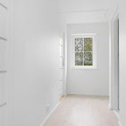 Ata Development - Jasny korytarz z białymi ścianami, panelami podłogowymi w odcieniach beżu, białymi drzwiami i oknem z widokiem na zieleń.