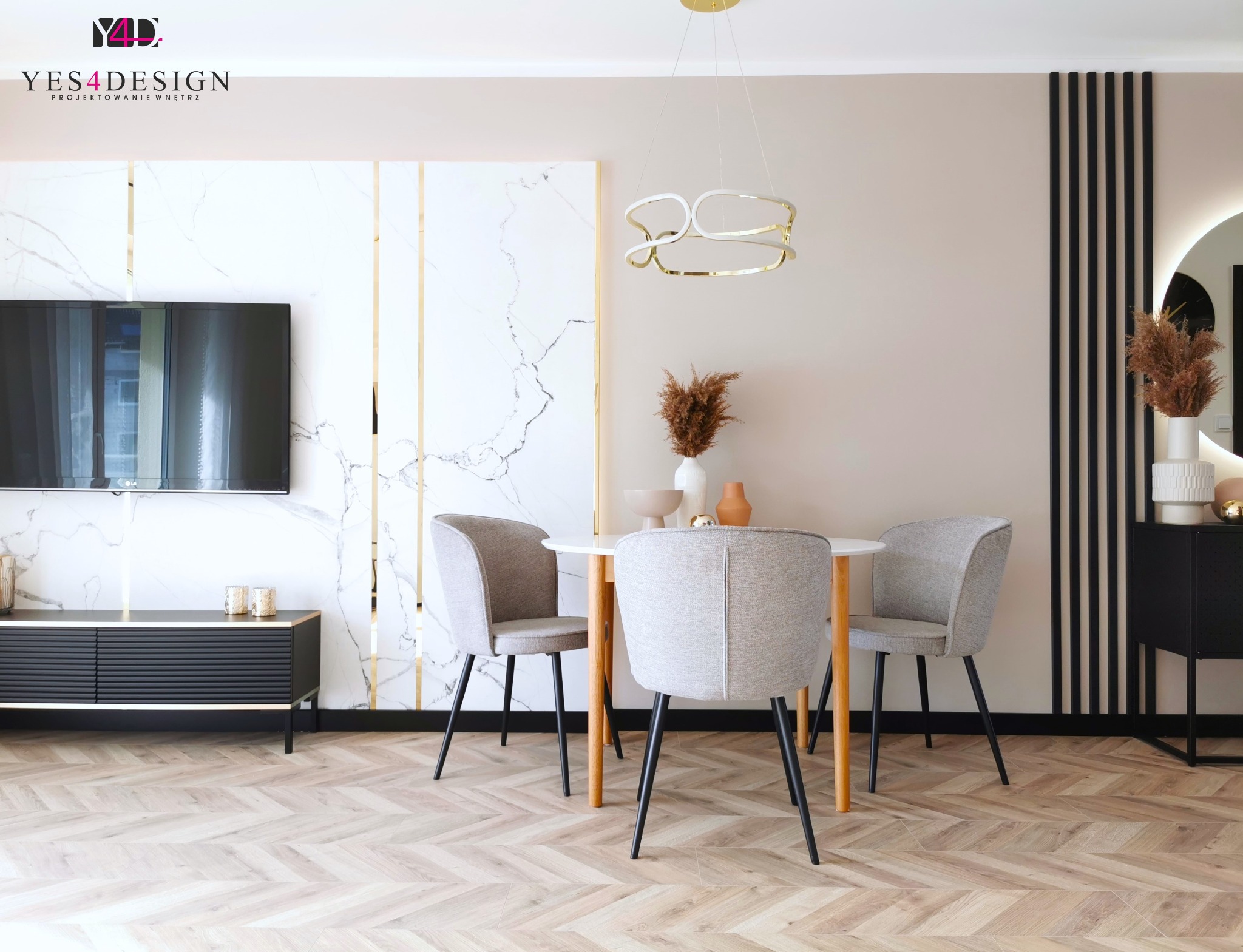Jadalnia w nowoczesnym stylu z okrągłym stołem, szarymi krzesłami, parkietem w jodełkę, marmurową ścianą z złotymi akcentami i czarnymi lamelami.