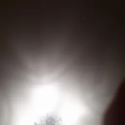 Niedoświetlone zdjęcie sufitu z widocznym fragmentem lampy i rozproszonym światłem.