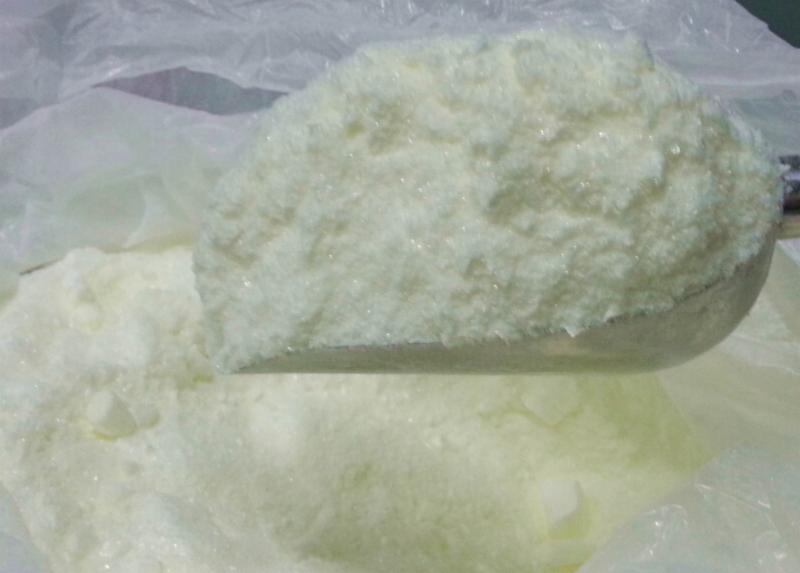 Biały proszek, prawdopodobnie kwas hialuronowy, w plastikowym worku, nabierany metalową łyżką.