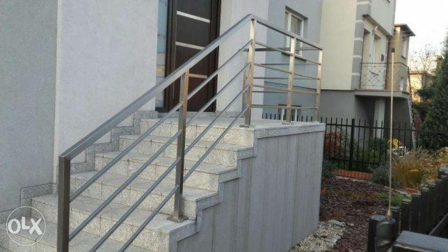 Zewnętrzna klatka schodowa z prostą, metalową konstrukcją zabezpieczającą, prowadząca do drzwi wejściowych budynku.