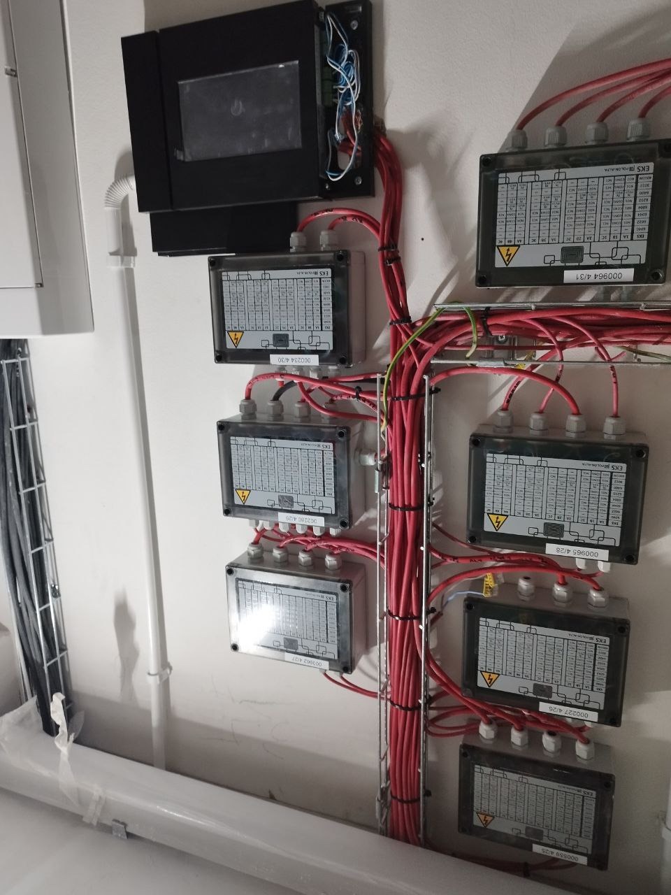 Rozdzielnica elektryczna z podłączonymi przewodami, widoczne oznaczenia na obudowach i kable ułożone w korytku.