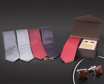 Zestaw prezentowy: pięć krawatów w różnych kolorach i wzorach (szary w kropki, jasnoszary gładki, czerwony w romby, granatowy w kratkę) oraz brązowe pudełko z czerwonym krawatem i spinkami...
